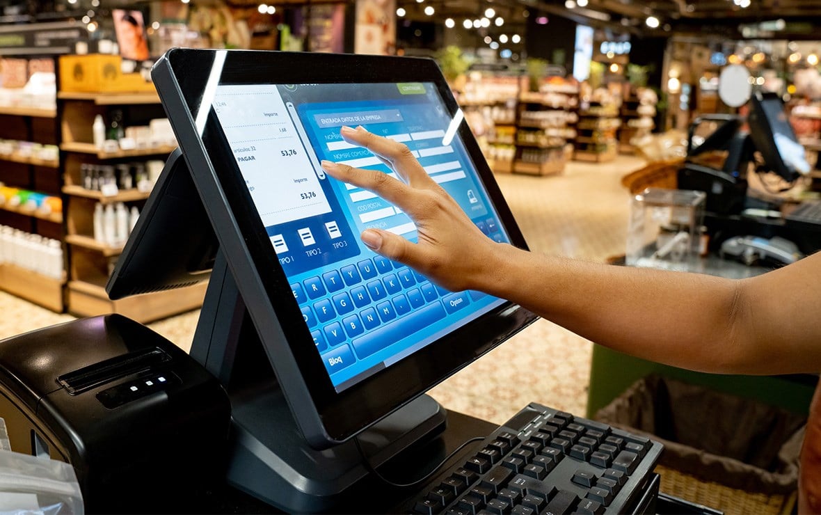 Hand touching a touch screen in a retail store.